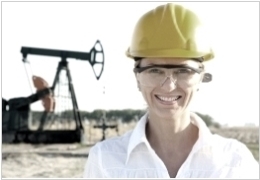 Female oil worker with helmet in front of a horsehead pump