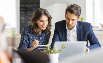 A business man and business woman discussing data on a laptop